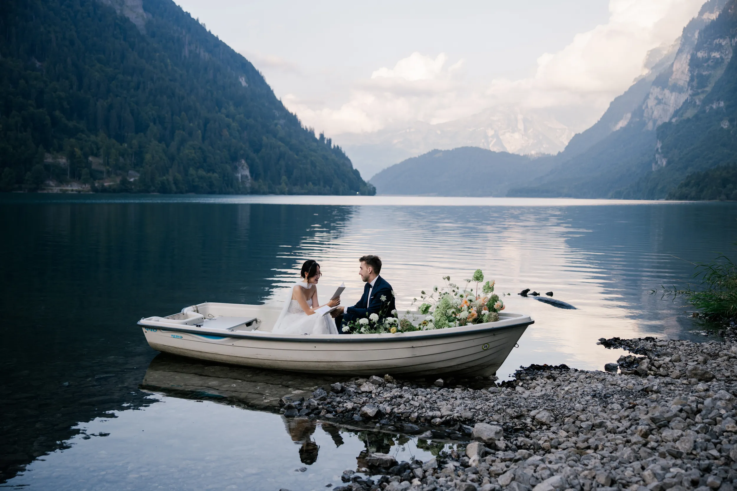 A wooden boat drifting on the mirror-like waters of Klöntalersee with towering Alps
