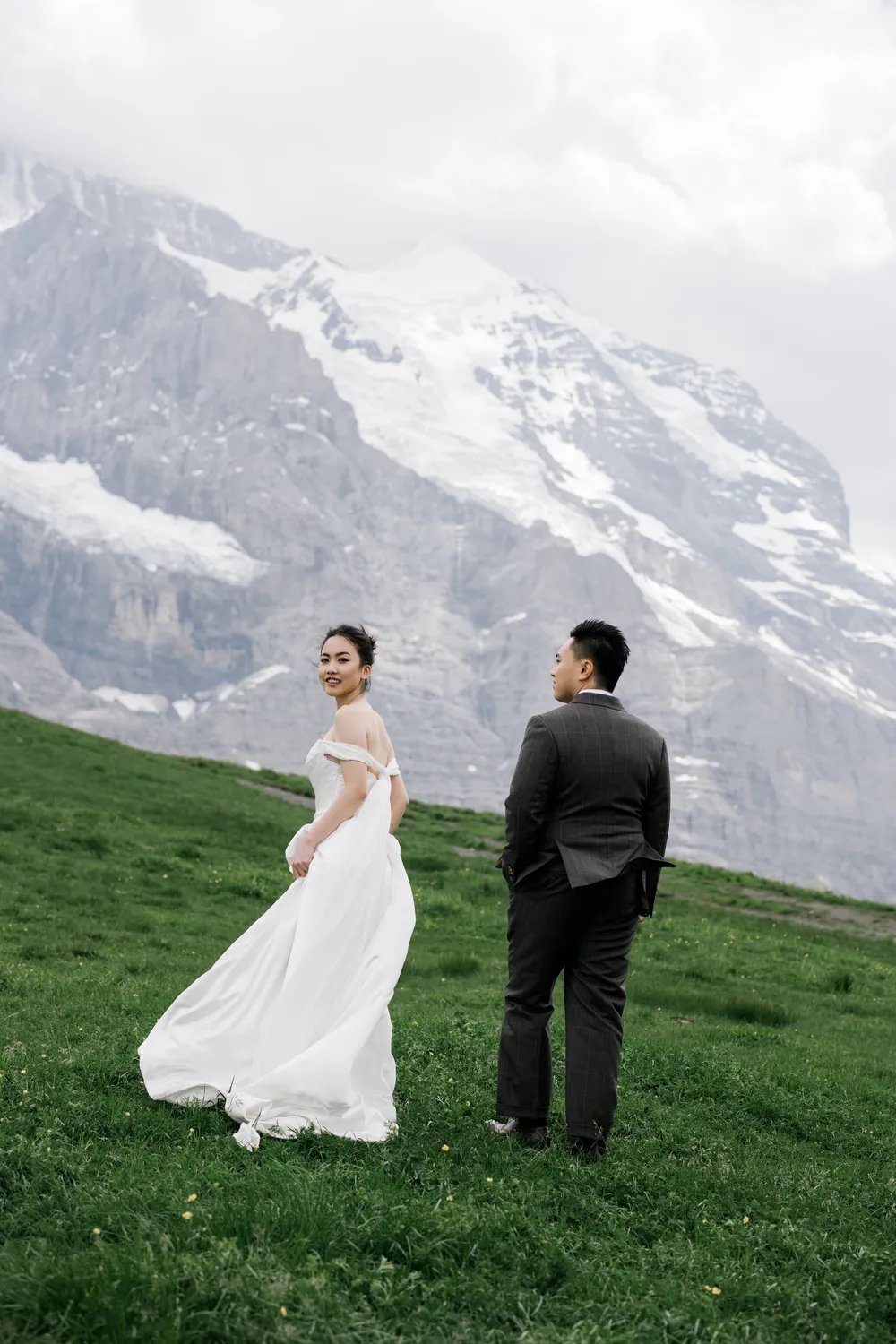 Bespoke **June** pre-wedding portrait with the snow-capped **Jungfrau** peaks and green meadows at Kleine Scheidegg.