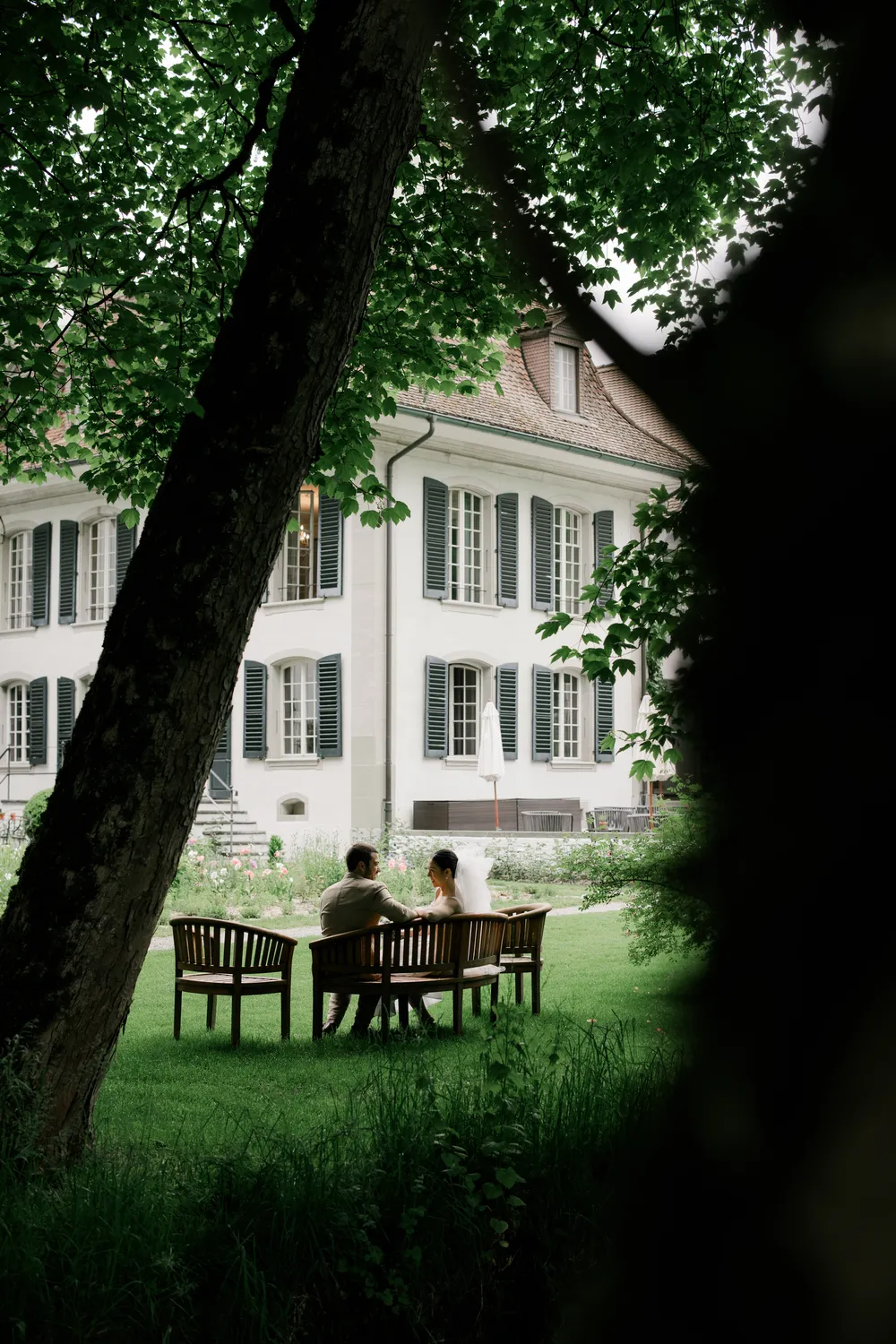 Atmospheric **wedding photography** under ancient trees at Schloss Hünigen, Bern, on a rainy May day.