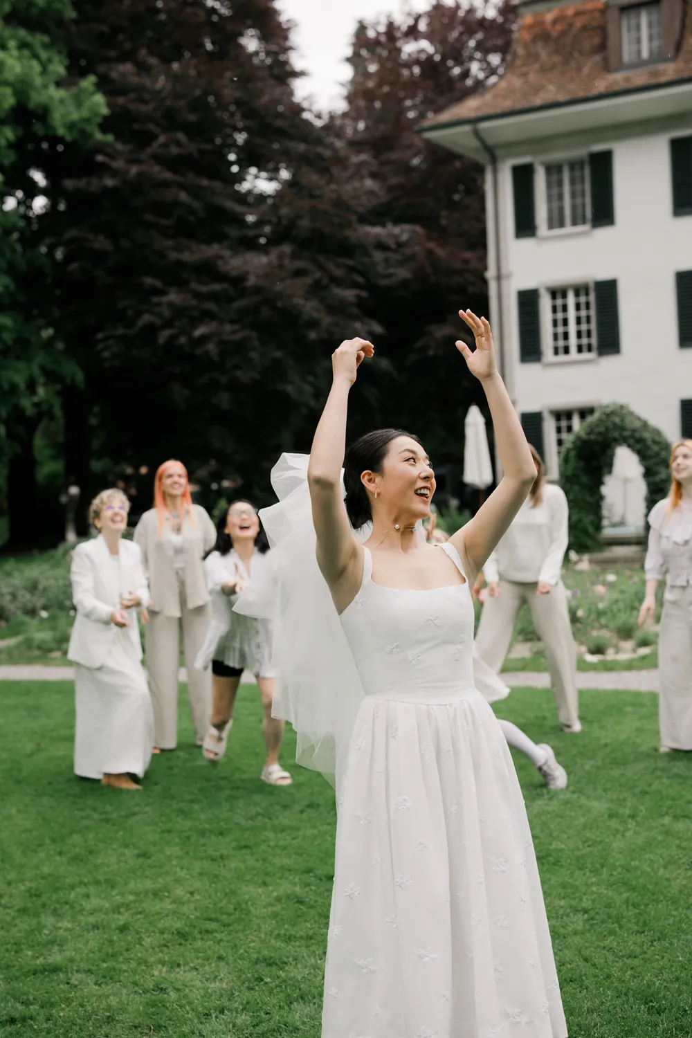 A bride tossing a lush bouquet of **peonies** during her wedding celebration at Schloss Hünigen.