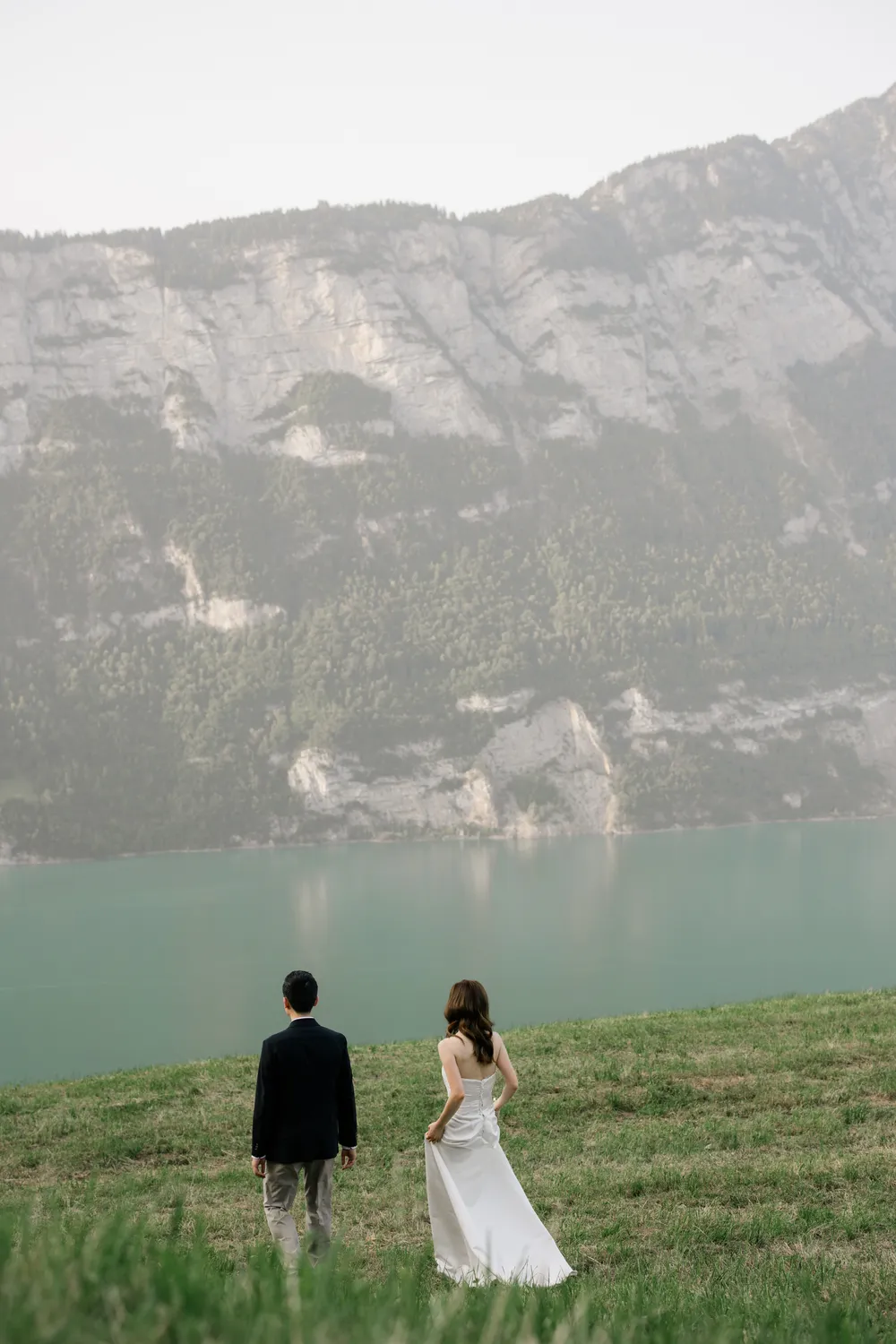 Cinematic black & white pre-wedding portrait of a Hong Kong couple against the misty Walensee backdrop.