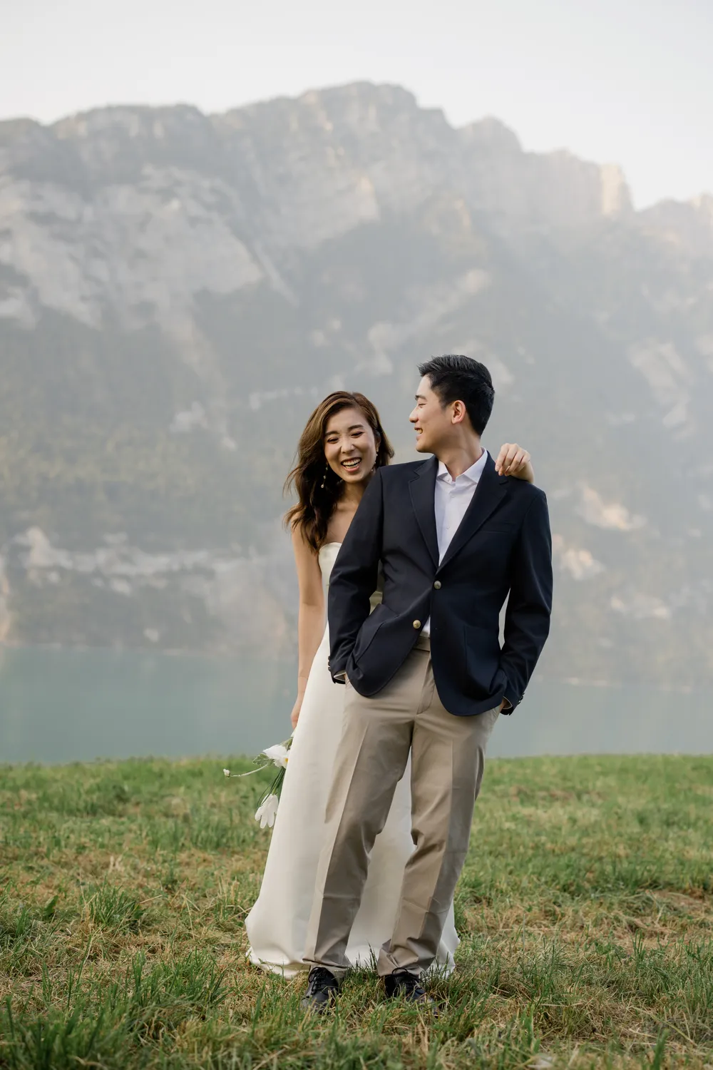 Romantic portrait of a Hong Kong couple in an alpine meadow overlooking the turquoise waters of Walensee in August.