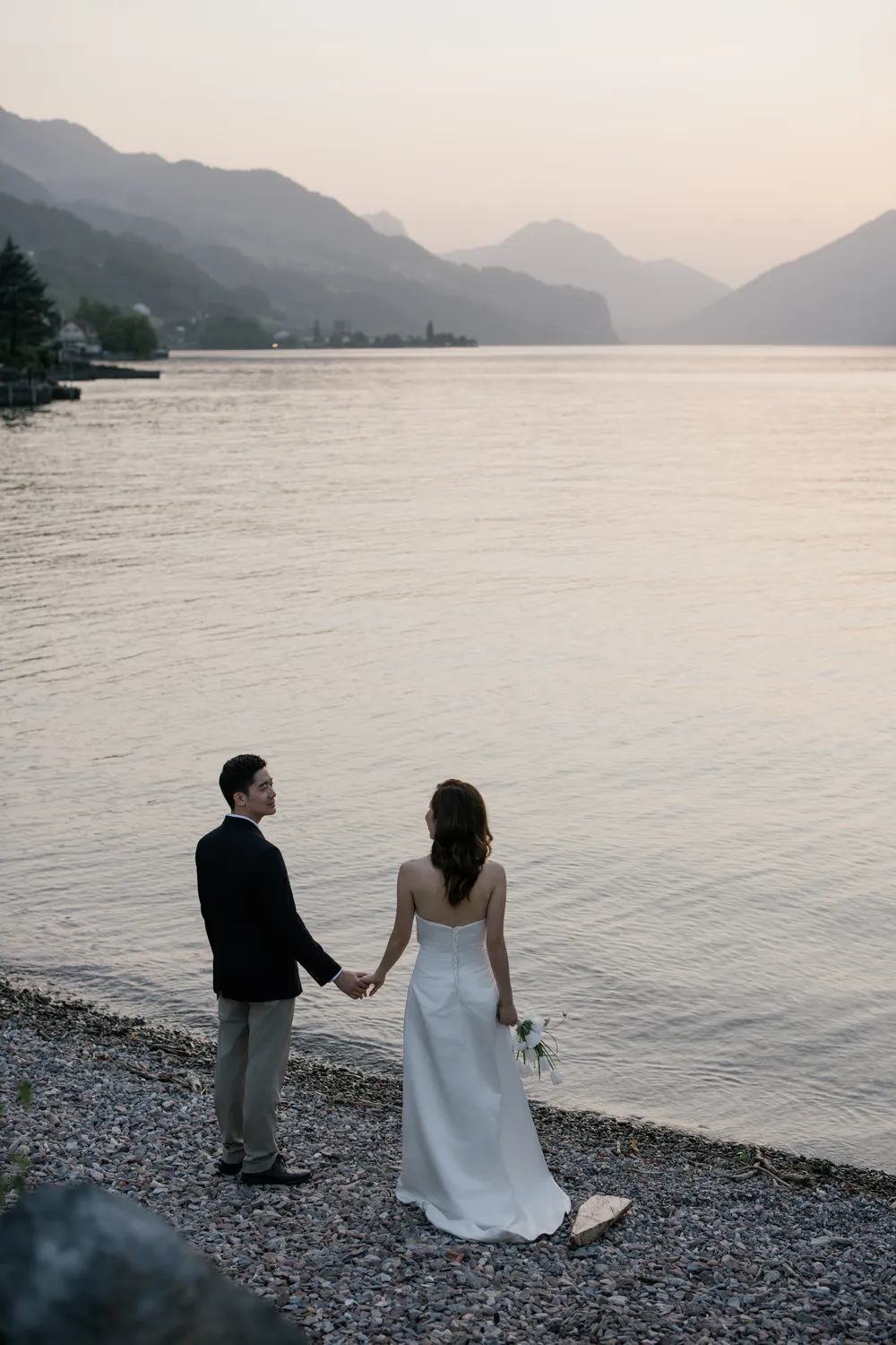 Bespoke pre-wedding portrait of a couple holding hands on beach with the dramatic Churfirsten peaks background at Walensee.
