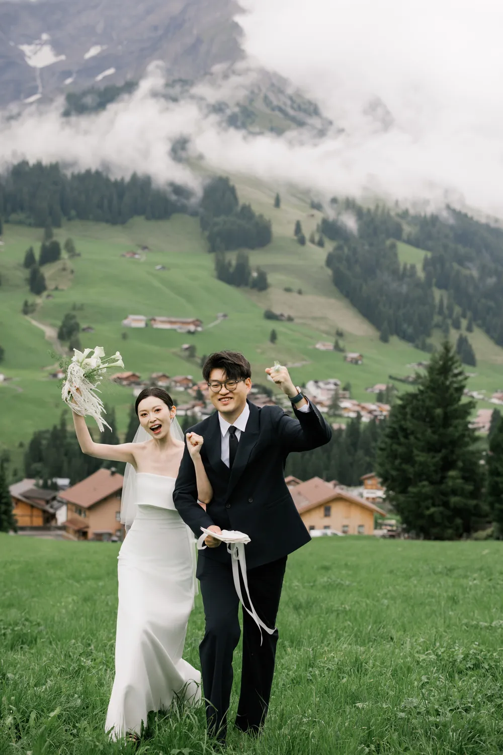 Joyful bride and groom running through Alpine meadows in Adelboden Switzerland